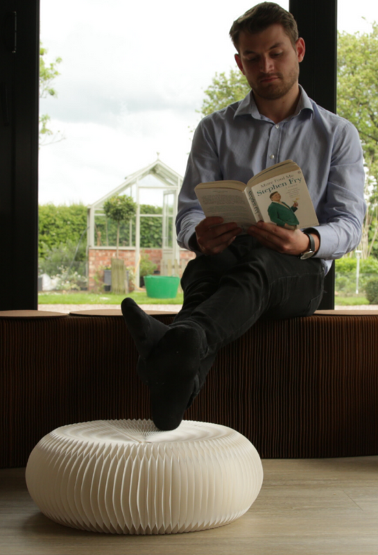 Man reading a book with his feet on a paper foot stool